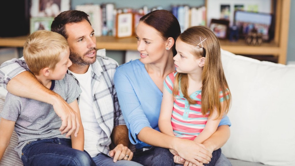 Vater, Mutter und zwei Kinder sitzen gemeinsam auf dem Sofa