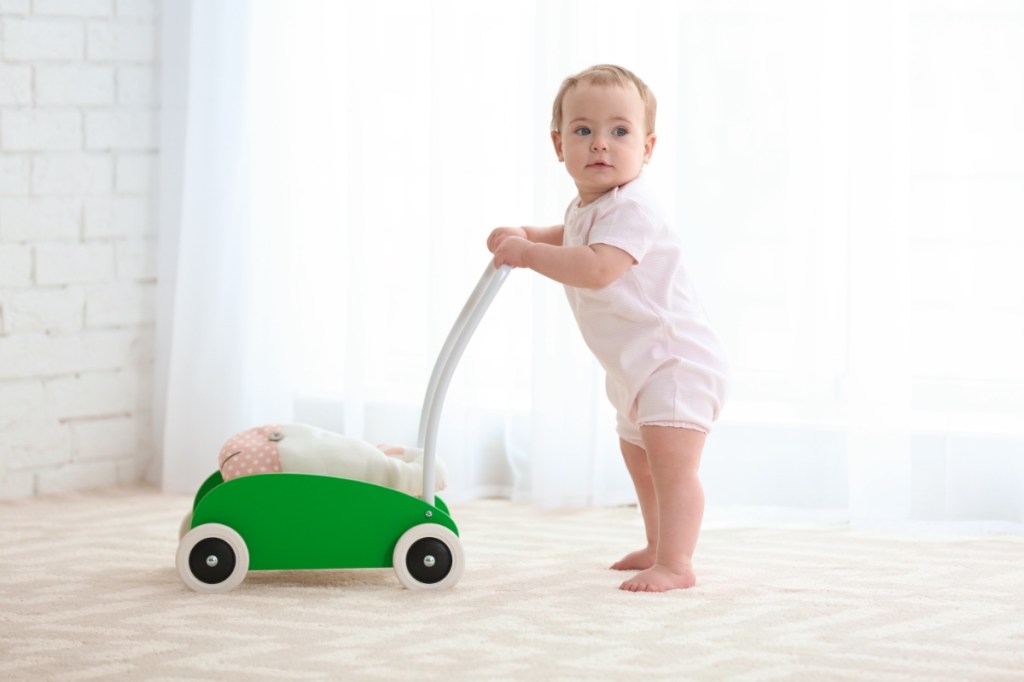 Ein Baby lernt Laufen mit einem Lauflernwagen.