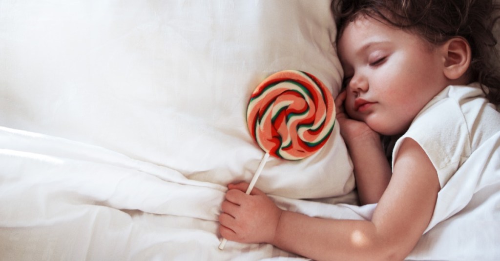 Baby schläft im Bett mit Lutscher in der Hand