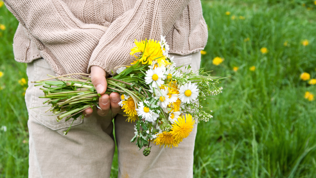 Eine Frau hält einen großen Wildblumenstrauß hinter ihrem Rücken versteckt.