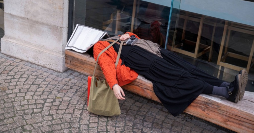 Müde Frau liegt auf einer Bank