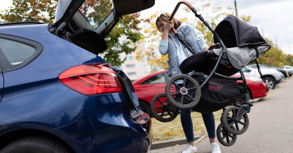 Frau verräumt Kinderwagen im Koferraum