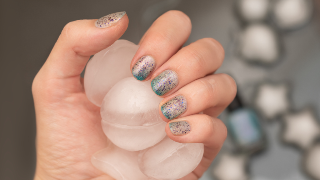 Eine Frau mit blauem Glitzer auf den Fingernägeln hält Eiskugeln in der Hand.