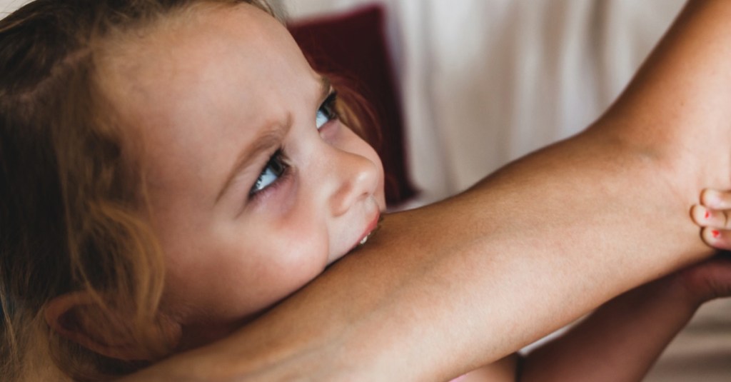 Kind haut oder beißt: Kleines Mädchen beißt der Mutter in den Arm