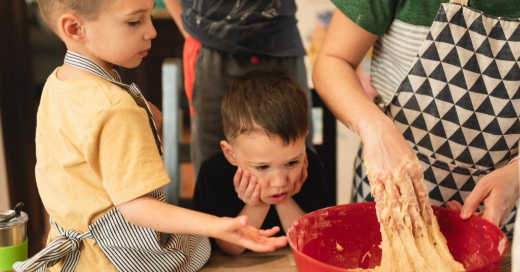 zwei Jungs schauen ihrer Mutter beim Kuchenbacken zu