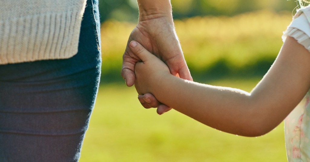 kleines Kind hält die Hand der Mutter