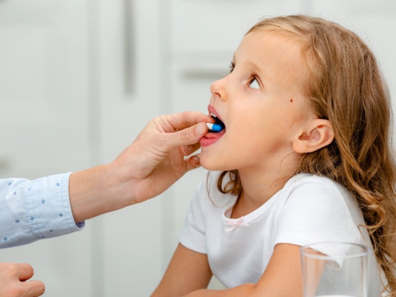 Vitaminpräparate für Kinder: Ein Mädchen hat eine Tablette im Mund