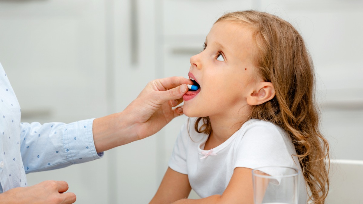 VitaminprÃ¤parate fÃ¼r Kinder: Ein MÃ¤dchen hat eine Tablette im Mund