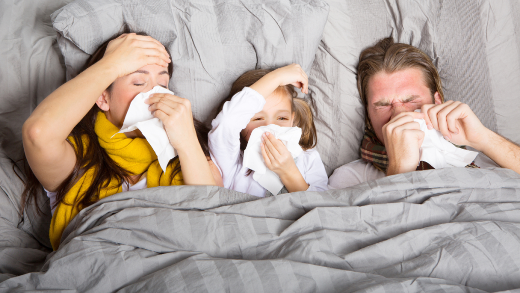 Mutter, Vater und Kind liegen krank im Bett.