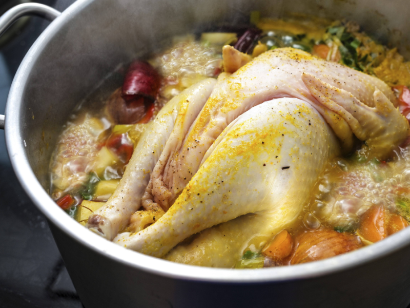 Hühnersuppe mit ganzem Huhn und Gemüse in einer Brühe