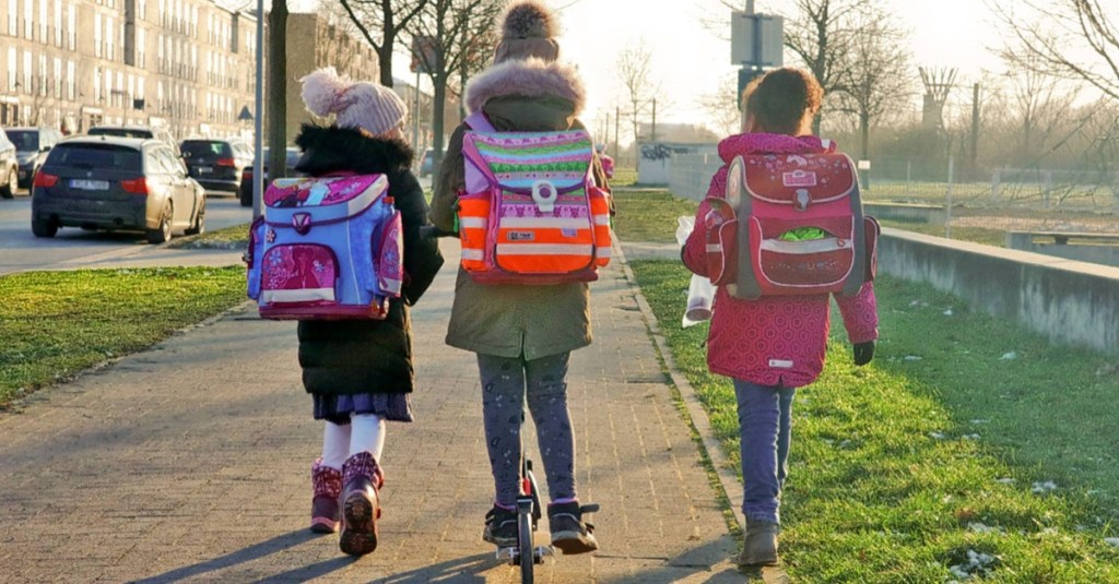 drei Mädchen mit Schulranzen auf dem Schulweg