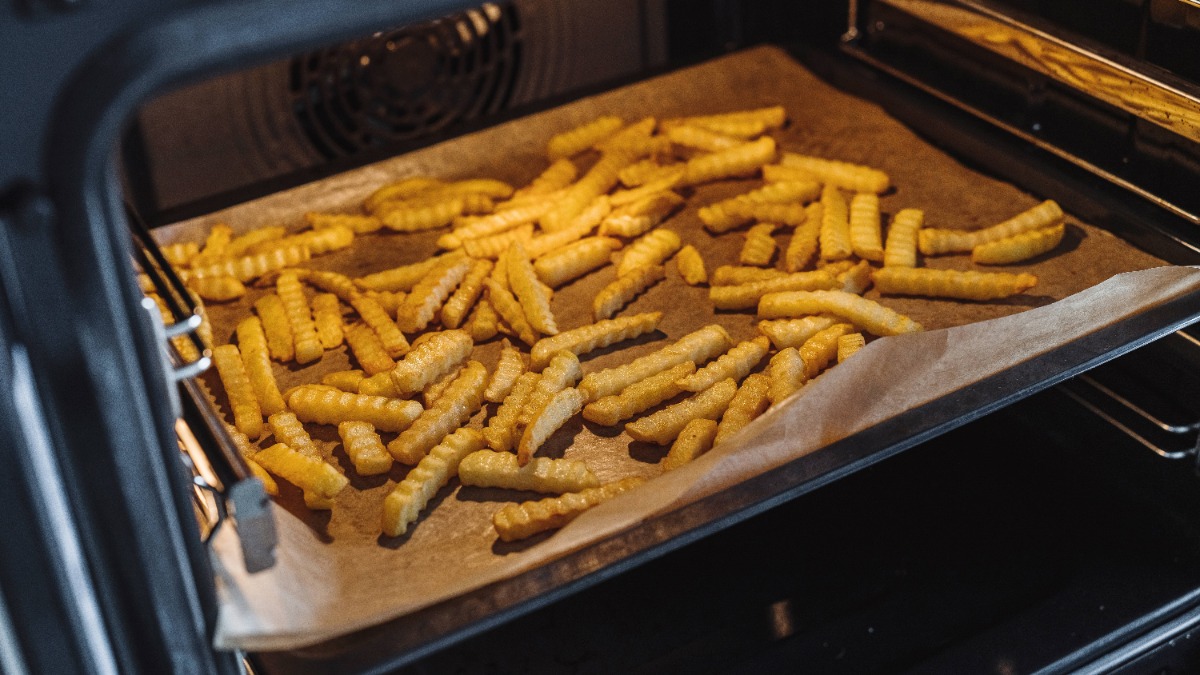 Pommes auf Backpapier auf einem Blackblech im Ofen