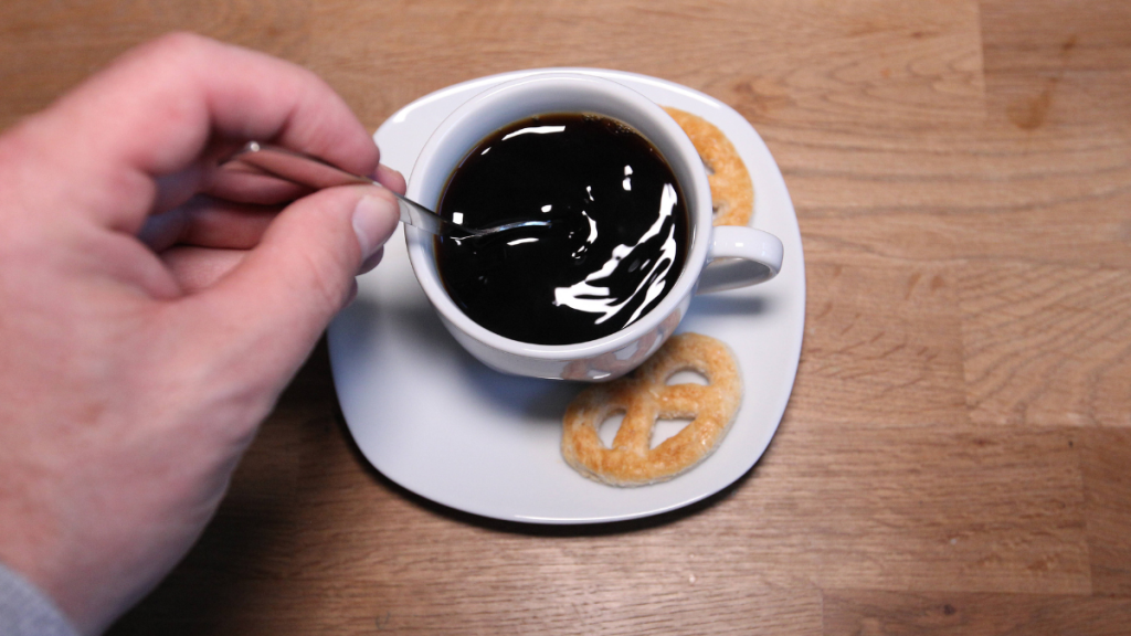 Kaffee schwarz mit Hand, die ihn umrührt