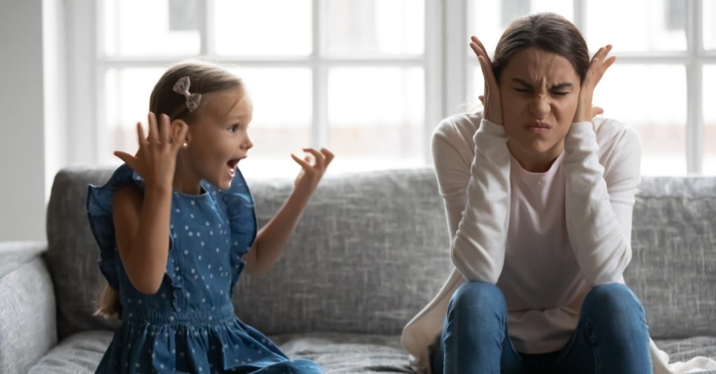 Mutter hält sich die Ohren zu, während ihre Tochter sie beschimpft.