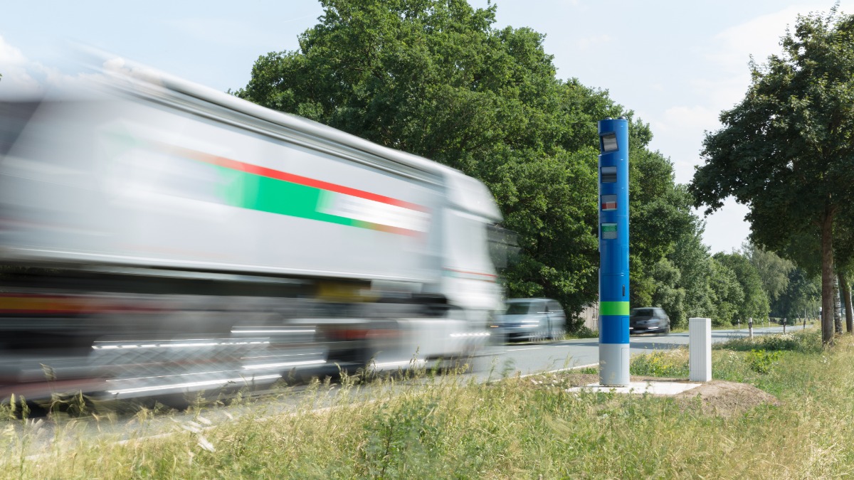 ein weißer Lkw fährt an einer blauen Säule am Straßenrand vorbei