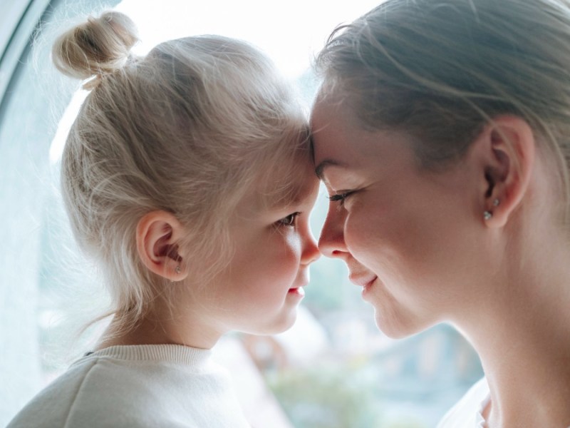 Geschenke für die Kinder: Mutter und Tochter halten ihre Stirn aneinander