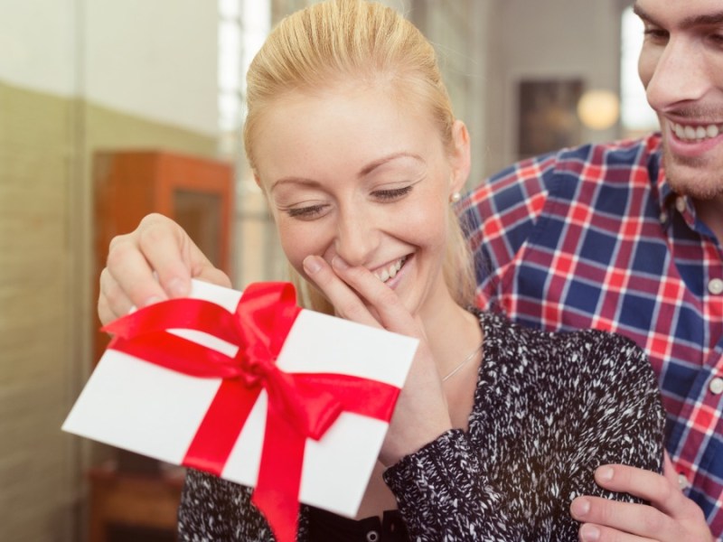 ein Mann überreicht seiner Freundin einen Geschenkgutschein