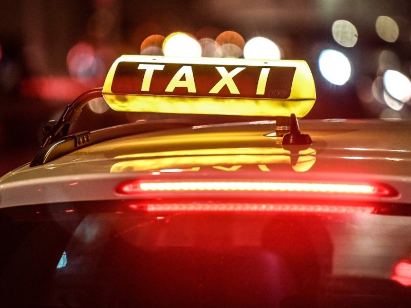 Taxifahrer: ein Taxi steht nachts an einer Straße