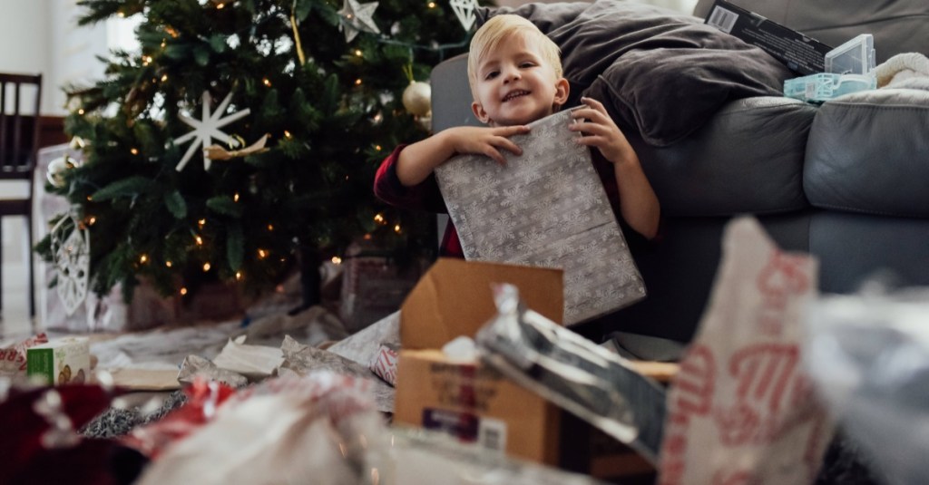 Kleiner Junge sitzt inmitten von Geschenken