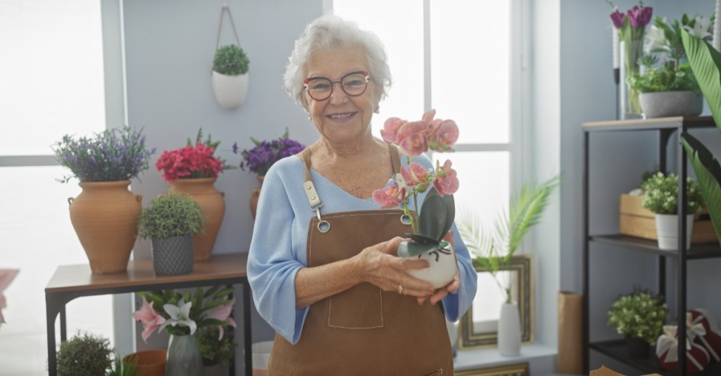 eine lächelnde Seniorin arbeitet in einem Blumenladen