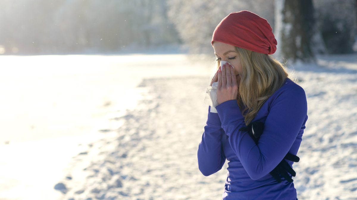 Eine Frau in Sportkleidung putzt sich im Freien die Nase.