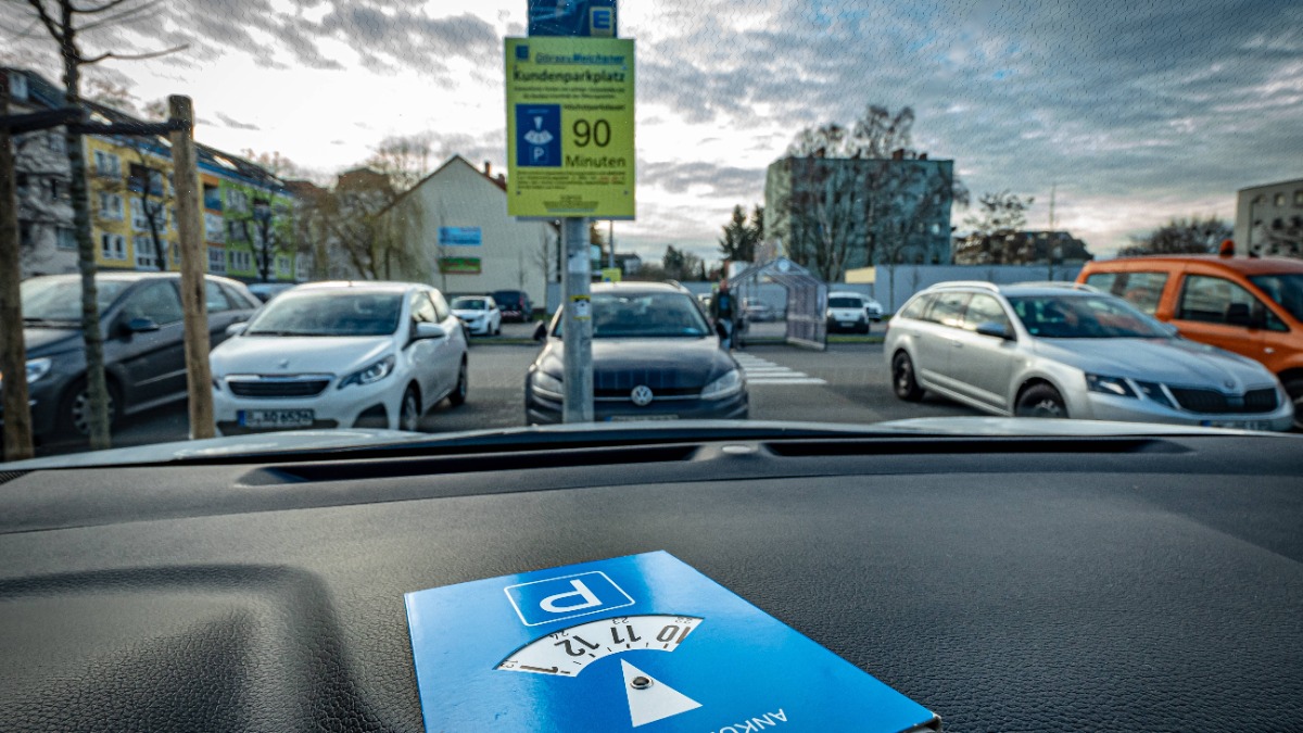 ein Auto steht auf einem Parkplatz, hinter der Windschutzscheibe ist eine Parkuhr