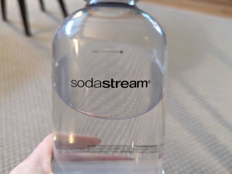 Eine Person hält eine Flasche von SodaStream.