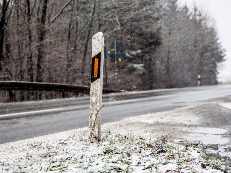 Leitpfosten am rechten StraÃŸenrand im Winter.