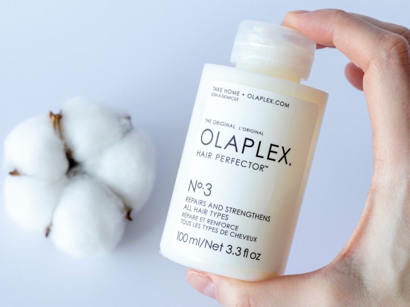 Eine Shampooflasche von Olaplex wird in die Kamera gehalten. Im Hintergrund liegt ein Baumwollbüschel.