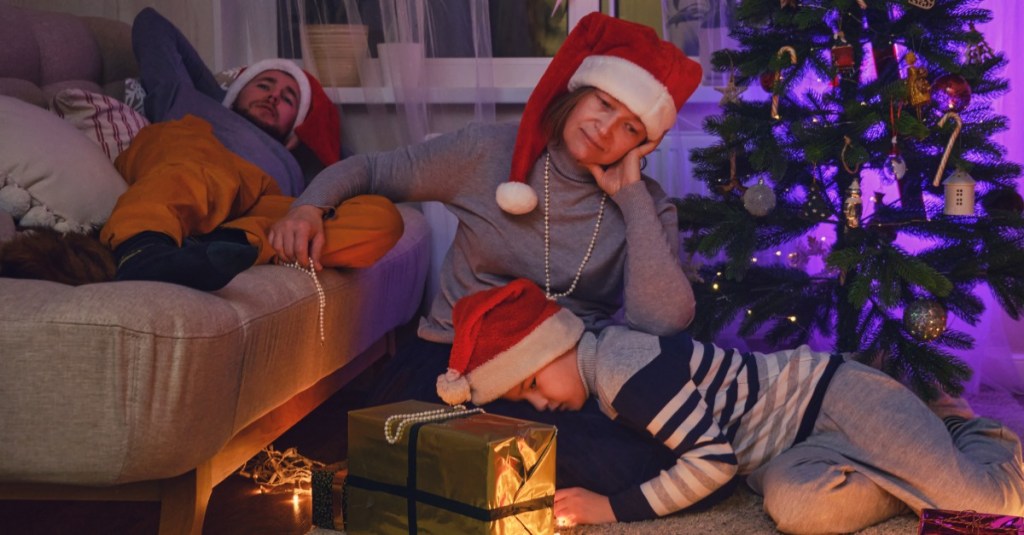 Eine Mutter sitzt mit ihrem Sohn vorm Weihnachtsbaum