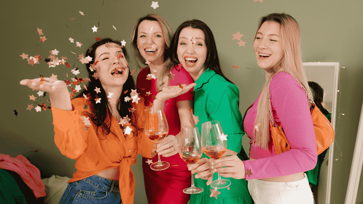 Galentine's Day, bunt gekleidete Frauen stoÃŸen an und werfen Konfetti