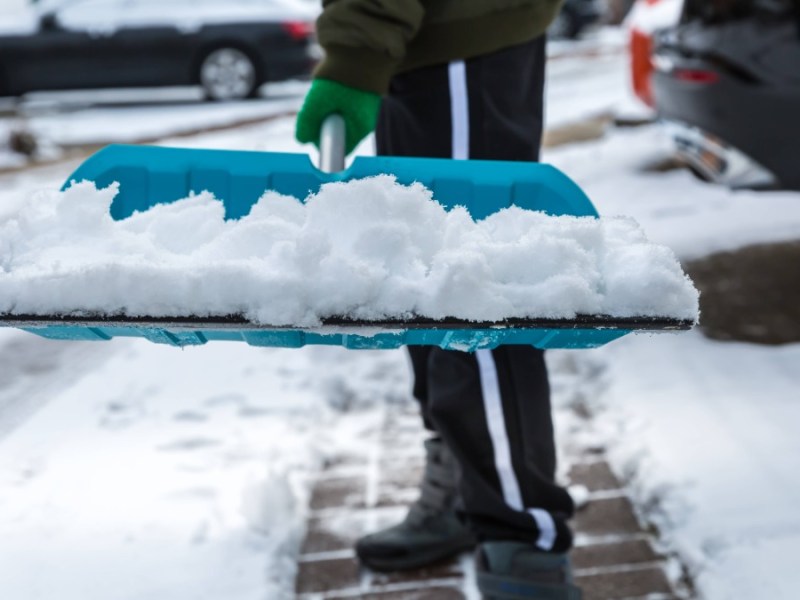 Schnee rÃ¤umen: Ein Anwohner befreit mit einem Schneeschieber einen Gehweg von Schnee