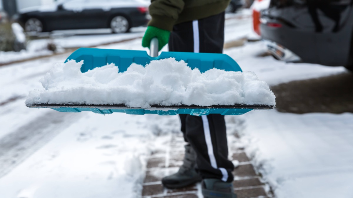 Schnee räumen: Ein Anwohner befreit mit einem Schneeschieber einen Gehweg von Schnee