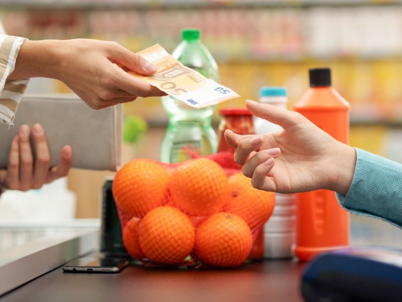 Eine Frau bezahlt mit einem 50-Euro-Schein an der Kasse im Supermarkt