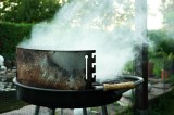 Ein rauchender Grill in einem Garten. Konzeptbild zur Frage: Ist Grillen im Garten erlaubt?