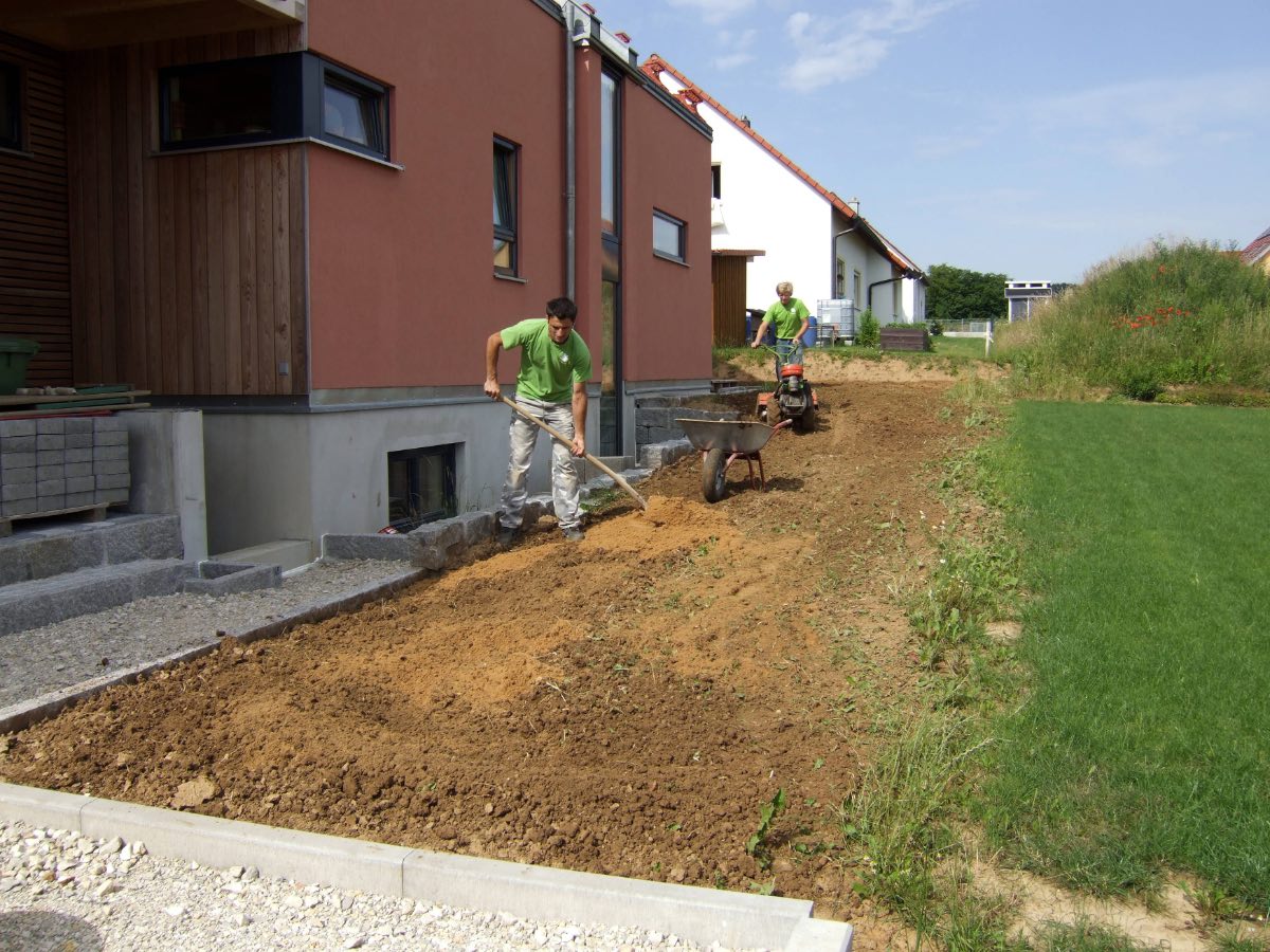 Zwei Gärtner beim Rasen anlegen vor einem Haus.